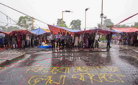 Agitators take cover during rains during sit-in demonstration against the RG Kar Hospital incident, outside Swasthya Bhavan in Kolkata, Friday, Sept. 13, 2024