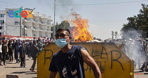 An protester watches police near burning barricades during a protest calling for the president to step down in Antananarivo, Madagascar, Thursday, Oct. 9, 2025