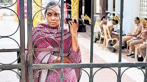 A detained employee talks over phone at a community marriage hall at Thirumangalam.