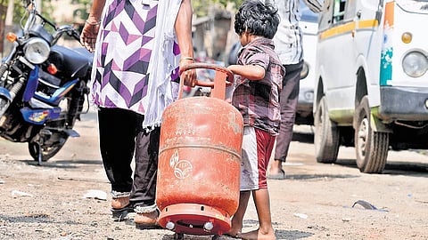 A boy lends a helping hand to his mother to roll an LPG cylinder in Puzhal.