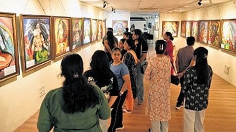 Visitors going through the paintings at the exhibition.