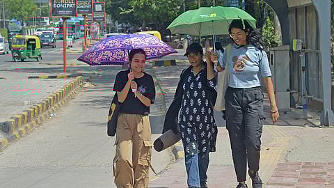 People use umbrellas as temperature rises in Delhi on Tuesday.