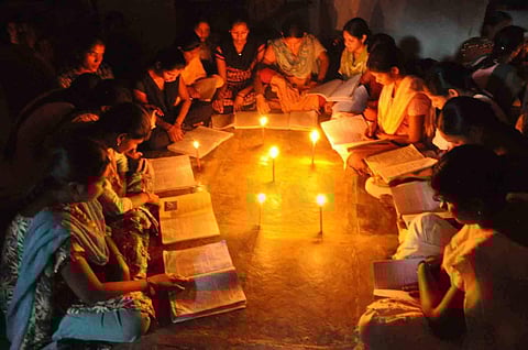 A group of students study by candlelight due to a power cut