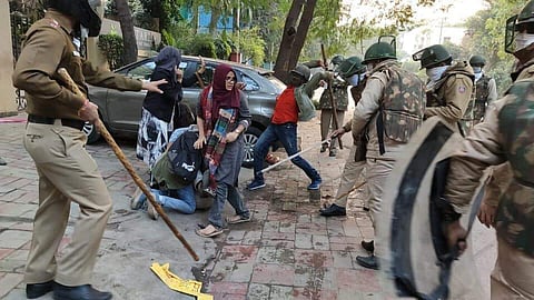 Screengrab from the video that shows the police hitting the studnt even though he is being shielded by the women (Facebook)