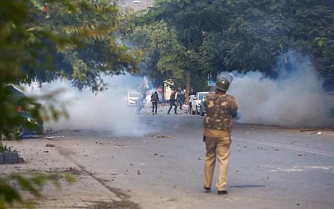 Policeman fires teargas shells at protestors of Citizenship Amendment Act at Mathura Road | Pic: PTI