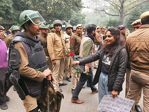 A protestor gives a rose to a Delhi Police personnel (Pic: Twitter)