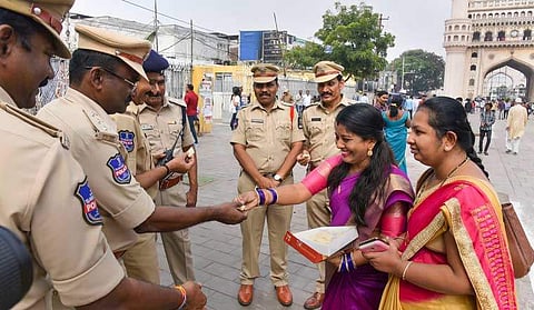 Women offer sweet to policemen after four accused in the in the gang rape and murder of a 25-year-old veterinarian were killed in an encounter | Pic: PTI