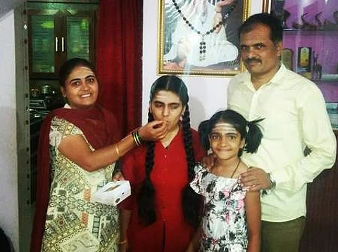 Basamma with her parents and sister celebrating her success by feeding sweets