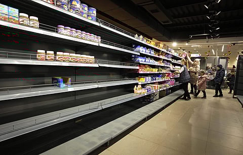 People walk next to nearly empty shelves at a shop in Nikolaev, Ukraine, Tuesday (Pic: AP)