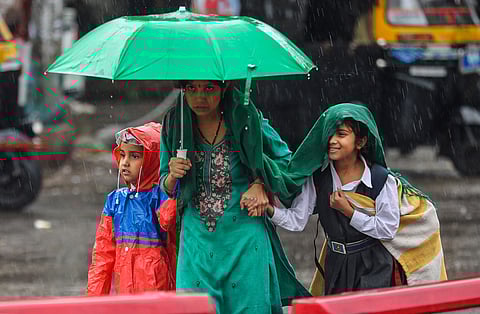 A woman with her children during rainfall, in Jammu, Monday, October 16, 2023 (PTI Photo)
