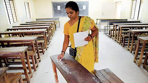 A staff writes register number ahead of SSLC examinations at a government school