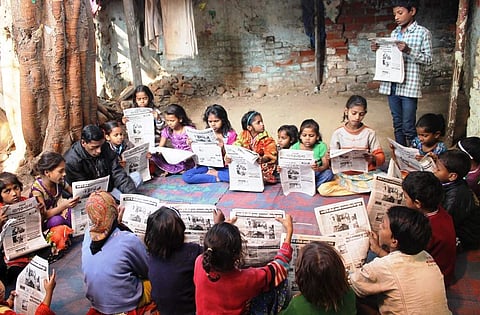 Children read a copy of their newspaper