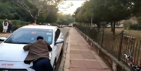 JNU VC's car backs up as the student clings to the hood (Pic: JNUSU)
