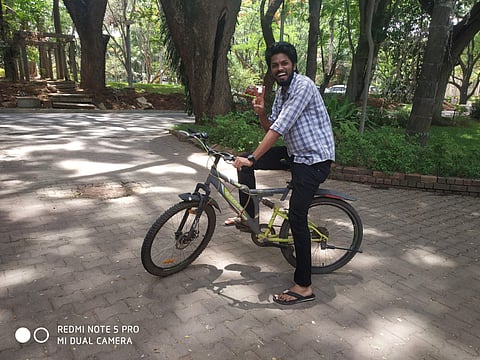 A student poses for a picture while riding his bicycle