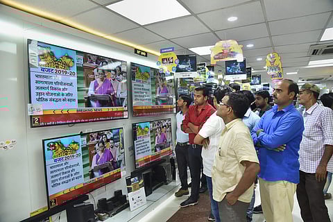 People watch Finance Minister Nirmala Sitharaman tabling the Union Budget 2019-20 on TV sets at a showroom in Patna (Pic: PTI)