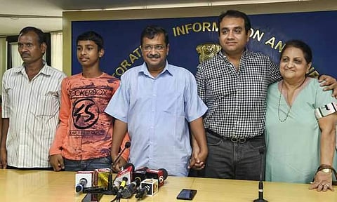 Delhi CM Arvind Kejriwal and Vijay Kumar, son of a tailor and a homemaker who cracked the IIT entrance examination, pose for a photograph during a press conference, in New Delhi on Sunday (Pic: PTI)