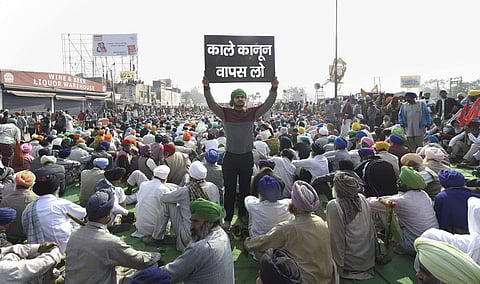 A farmer holds a placard at Singhu border during 'Delhi Chalo' protest march against the Centre's new farm laws, in New Delhi, Wednesday (Pic: PTI)